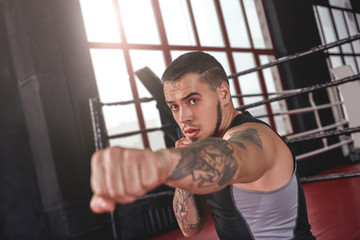 Good jab. Muscular athlete in sports clothing throwing jab punch in boxing gym. Confident boxer...