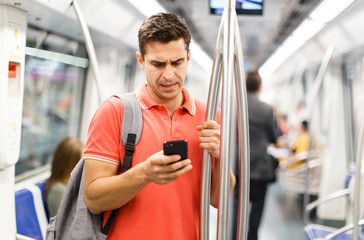 Male is traveling and standing with mobile in the train