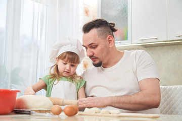 Obraz na płótnie Canvas father preparing food with my daughter. a man teaches a child to cook. the process of cooking in a bright kitchen. home cooking is the father of one daughter and love to cook