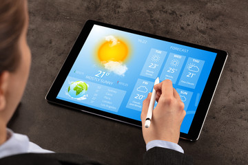 Fototapeta na wymiar Business woman checking weekly weather forecast on tablet 