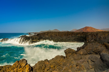 Fototapeta na wymiar Spain, Lanzarote, Splashing giant waves breaking in volcanic bay of los hervideros