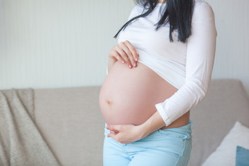 Young pregnant woman indoors. Closeup portrait of woman expecting. Beautiful female waiting for her little baby birth.