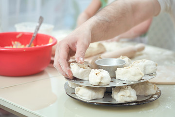 Obraz na płótnie Canvas Uzbek national food manta, like dumplings, on a special steamer, a man's hand puts manta rays on a circle