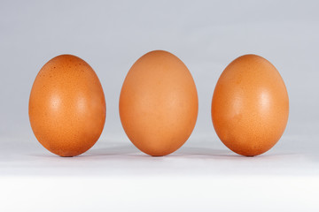 Three light brown chicken eggs on a white background