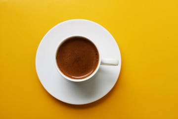 Cup of coffee on color background, top view, hot drink