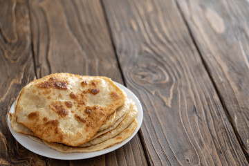 on a plate are fried bread cakes, wooden textured table. with free text, copy space,