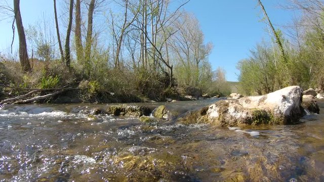 Panning over water on a flowing river with rocks, La Muga, Girona, Alt Emporda, Catalonia, Spain