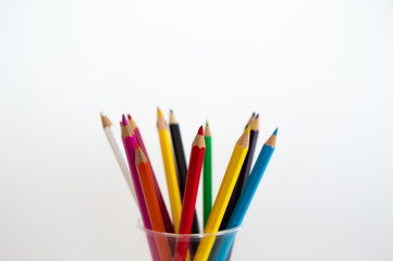Colored wooden pencils for drawing in a glass stand on a white background. Children's multi-colored pencils for drawing.