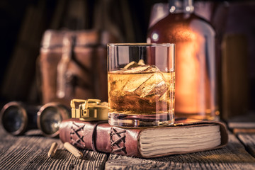 Closeup of whisky with ice on old journal