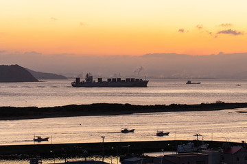 朝焼けの海峡を航海する巨大な船