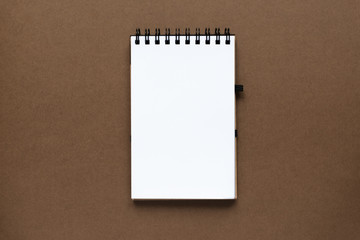 Top view of open empty notebook with cover from recycled paper on brown colorful background