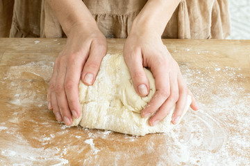 female hands knead the dough on a wooden board cooking baking