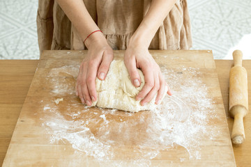 female hands knead the dough on a wooden board cooking baking