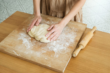 female hands knead the dough on a wooden board cooking baking