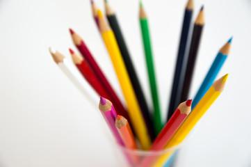 Fototapeta premium Colored wooden pencils for drawing in a glass stand on a white background. Children's multi-colored pencils for drawing.