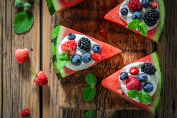 Homemade watermelon pizza with berries, whipped cream and mint leaves