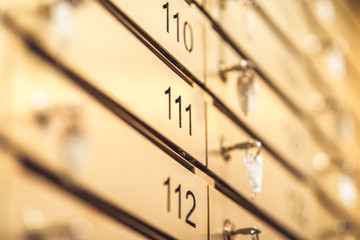Row of golden numbered lockers with keys - shiny stainless steel metal for keep mail or something important. Selective focus macro shot with shallow depth of field