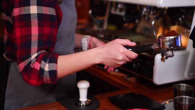 Professional female barista making coffee with espresso filter machine in slow motion
