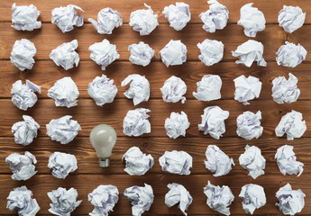 Ideological concept with wastepaper light bulb on wooden table