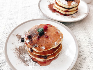 Delicious pancakes with syrup and berries on stylish plate on rustic table. Yummy homemade...