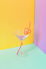 Cocktail glass with funny pink liquid and drinking straw. Strong fashion shadows. Concept of luxury relax with beverage on the beach.