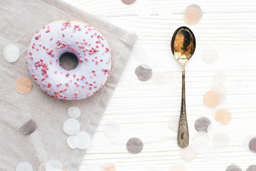 Delicious colorful purple donut with sprinkles  on stylish white table with confetti and vintage...