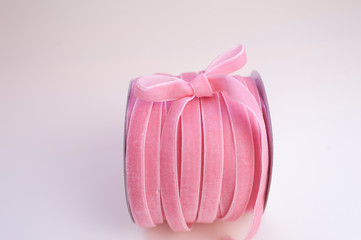 a roll of velvet pink ribbon for floristics and gift wrapping with a cute bow on the side. White...