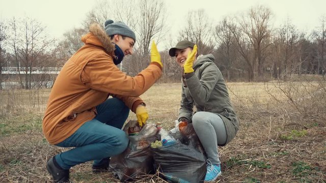 Couple picking up trash in park. Gathering garbage in bags. Challenge.