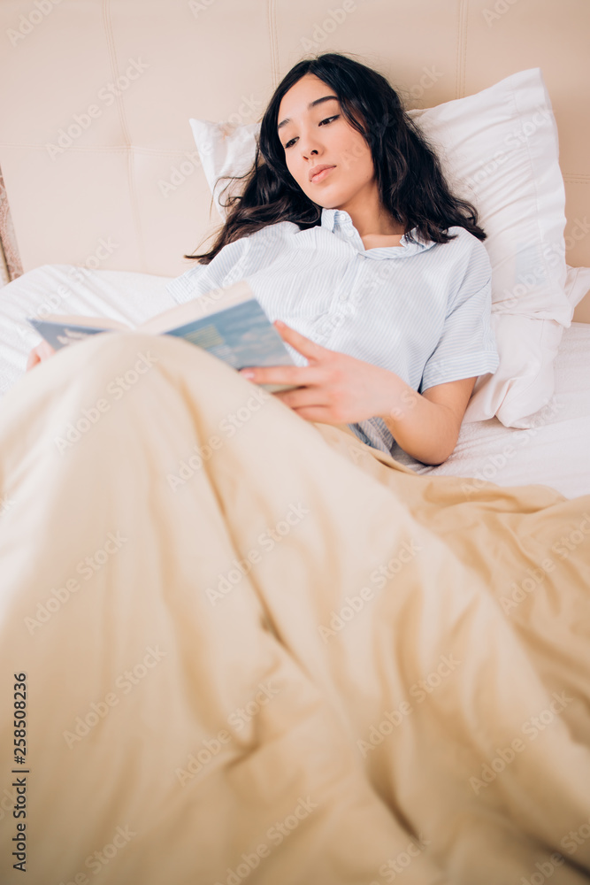 Wall mural Portrait pretty young girl on bed in modern apartment in the morning