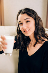 Charming smiling brunette girl with french manicure holding glass of milk. Health care, diet,...