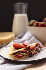 crepes with strawberries and chocolate cream, black background