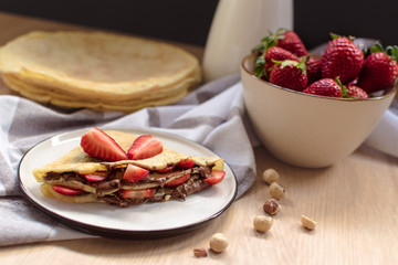 crepes with strawberries and chocolate cream, black background
