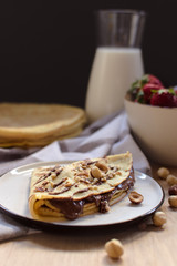 crepes with strawberries and chocolate cream, black background