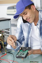 computer technician on the phone while he repairs a pc