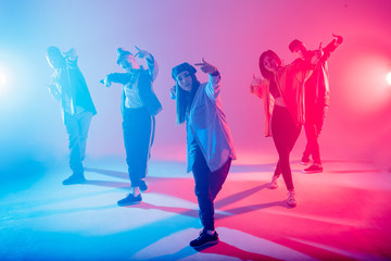 Animation group of young women and men dancing over red and blue dual color light on dark background