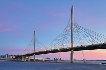The bridge of circle highway road over Neva river near the mouth of it in the blue hour after the sunset. Night view on the buildings of Petersburg city and the Finish gulf