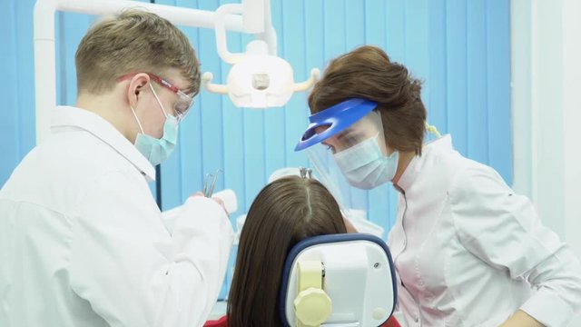 Man and woman dentists in masks and goggles. Media. Partners dentists in protective sterile uniform with equipment ready to get to work