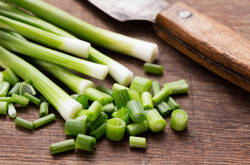 green onion with knife on wooden background