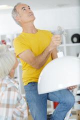 senior male doing home repair - lamp