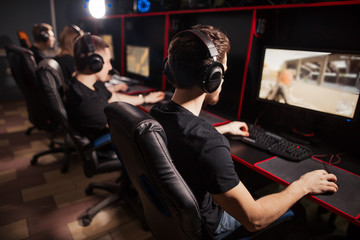 Professional Gamers participating in online cyber games tournament, sitting at pc gaming club or in...