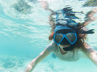Fototapeta premium woman taking an underwater selfie while snorkeling in crystal clear tropical water