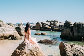 Junge frau sitzt auf einem Felsen am Boulders Beach in Kapstadt