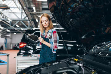 good looking girl holding a tablet and examining the car, close up photo, copy space