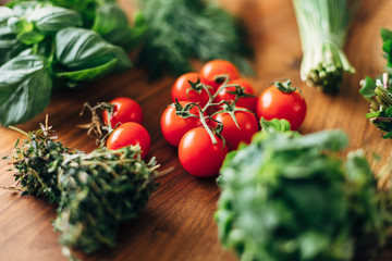 Ripe cherry tomatoes with herbs on a wooden table