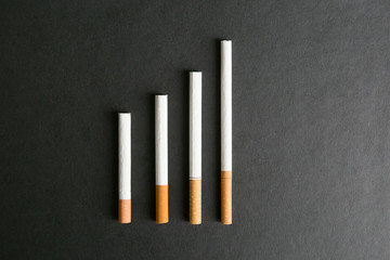 Cigarettes lie on a black background. Several cigarettes stacked neatly on a black background.
