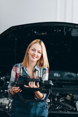 happy girl using a tablet while fixing a car, close up photo