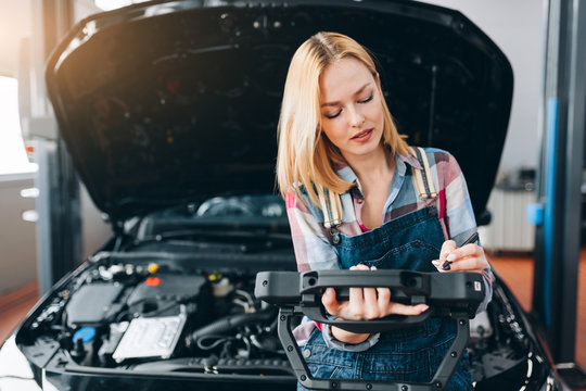 cute gorgeous girl looking for a problem of car, close up photo. copy space. working day at the garage