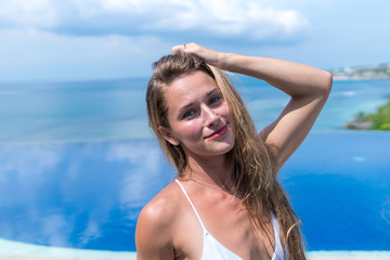 Naklejka premium sexy girl. beautiful woman. model lady bikini underwear sit edge of water swim pool on the roof of luxury resort hotel nice sea scenery long shot