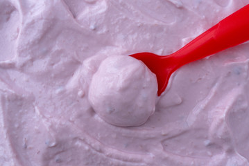Red raspberry yogurt with a spoon in the food close view