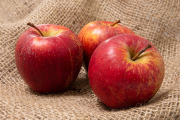 Close up of 3 red apples on a natural hessian bag showing concept of fresh organic fruit